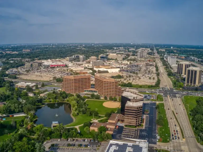 Aerial view of a suburban office park with multiple buildings, a pond, and a baseball field.