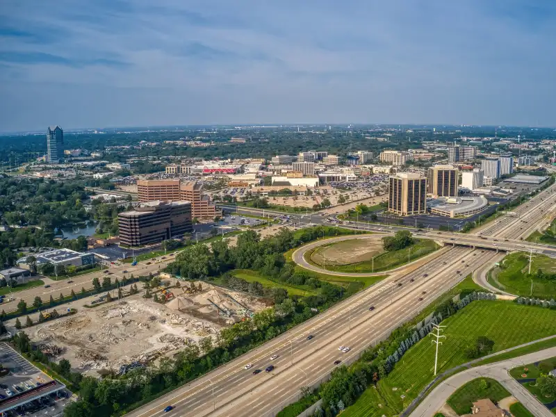 Aerial view of a highway interchange with office buildings and greenery surrounding it.